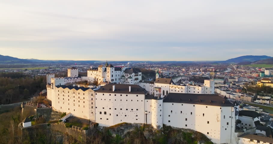 Aerial view Hohensalzburg Castle in Salzburg Austria. Ancient fortress on the top of the mountain at sunset in the landscape of the city and mountains of the Alps. High quality 4k footage