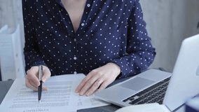 Unrecognizable business woman examining paperwork in an office setting with her laptop open. Professional woman reviewing documents at desk - Powered by Shutterstock - Get 15% off with code: PIKWIZARD15