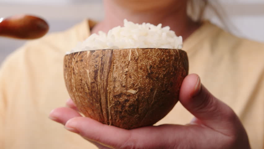 Woman eating boiled rice with wooden spoon from bowl for lunch close-up. Royalty-Free Stock Footage #3469312893