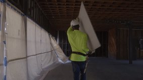 Construction worker carries drywall, stock video