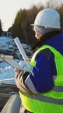 A woman working as a civil engineer or an inspector at the construction site of a main gas pipeline checks the plan. Vertical video, shorts.
