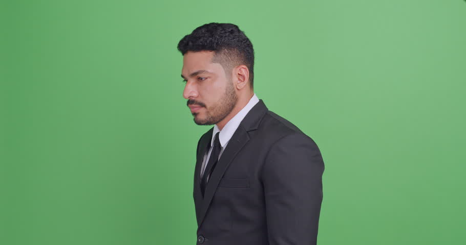 Portrait of handsome young Asian businessman in a black suit. Isolated on green background in studio.