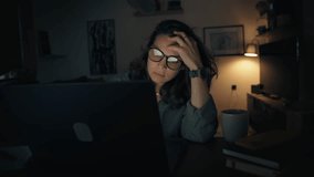 A tired young woman is working on a laptop while sitting in the living room late at night. - Powered by Shutterstock - Get 15% off with code: PIKWIZARD15
