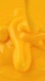 Pour yellow cheese sauce, close up. Vertical video