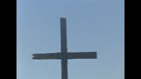 Old video clip zooming out on a cross against a blue sky