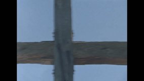 Old video clip of a close up of a wooden cross against a blue sky