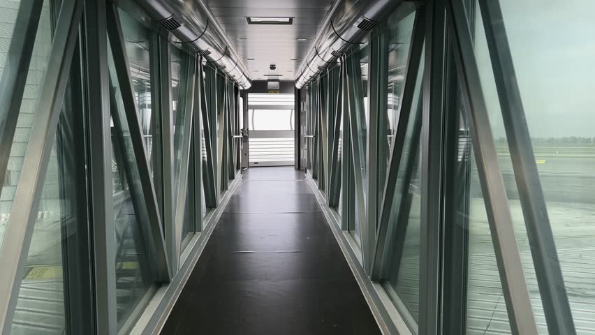 First-person POV walking inside empty and inoperative passenger boarding bridge without airplane