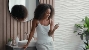 African American laughing happy smiling woman reading funny news mobile phone fun laugh smile joy watching video smartphone video call conference girl telephone social media humorous joke in bathroom