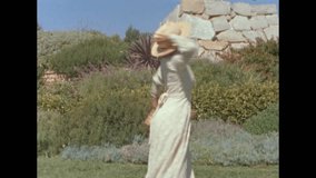 Old film video of a woman twirling around with a briefcase and sun hat