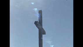 Old video clip of the side of a wooden cross against a blue sky