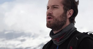 Detail of man face panting, resting and looking away.Mountaineering ski activity. Skier people winter sport in alpine mountain outdoor.Slow motion 60p 4k video