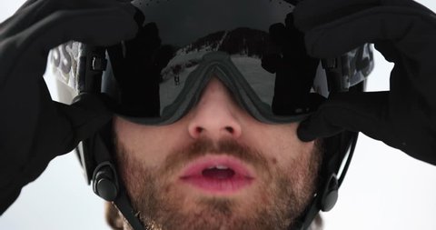 Man face detail adjusting helmet preparing for skiing.Mountaineering ski activity. Skier people winter sport in alpine mountain outdoor.Front view.Slow motion 60p 4k video