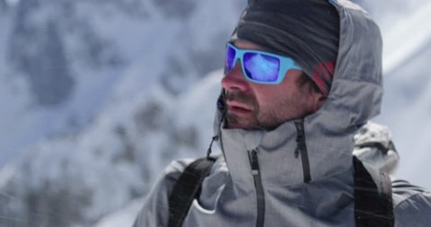 Climber mountaineer man portrait on snowy mount top in sunny day.Mountaineering ski activity. Skier people winter snow sport in alpine mountain outdoor.Side view.Slow motion 60p 4k video