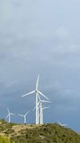 Vertical video of a group of windmills on top of a hill with a dramatic electric blue sky in the background. High-quality FullHD footage