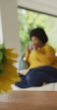 Vertical video of plus size biracial woman drinking coffee at home. spending active time at home and body inclusivity.