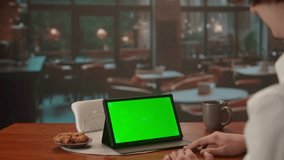 Video call on tablet with green screen in evening cafe. Advertising area, workspace mock up.