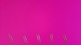 Paper clips move at the bottom of the pink background. Lots of free space for design, inserting text, advertising, messages. Template with the concept of study, paper work, documents.