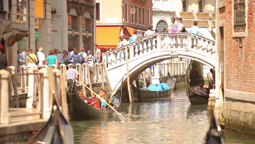 VENICE - MAY 2, 2012: Gondolas pass under a bridge