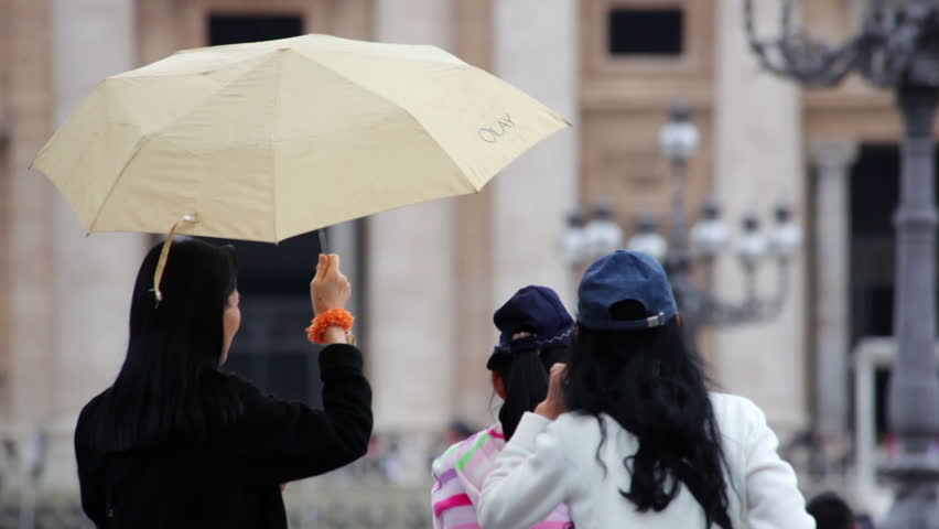 VATICAN CITY - CIRCA MAY 2012: A woman uses an umbrella to shield another woman