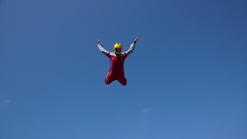 Man in a Skydiving Suit Flies in the Air Above a Vertical Wind Tunnel. Vertical Wind Tunnel Allows to Experience Flying Like a Bird Over Treetops, Under the Blue Sky.