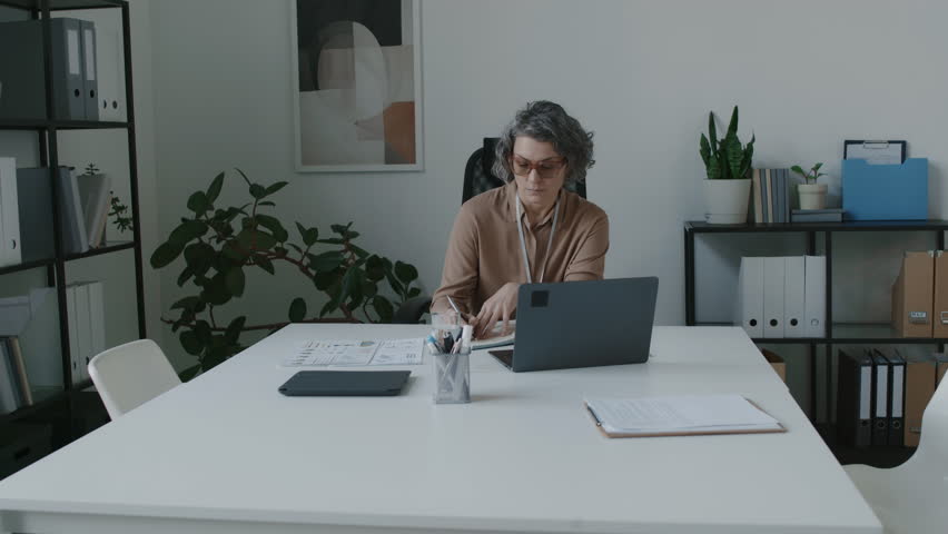 Full shot of Caucasian female clinic executive sitting and working in office, multiethnic male chief physician and medical director walking in, sitting down, preparing to speak on current agenda Royalty-Free Stock Footage #3469917343