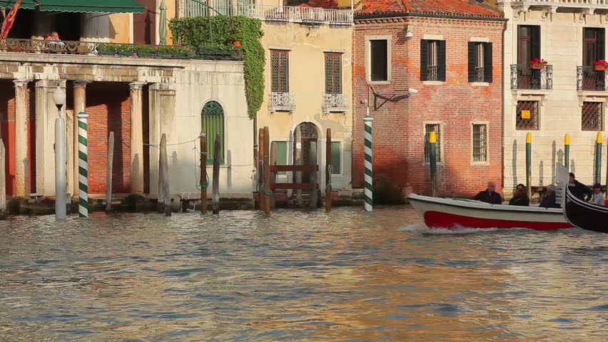 VENICE - MAY 2012: Locked-down shot of a single motor boat and gondola moving