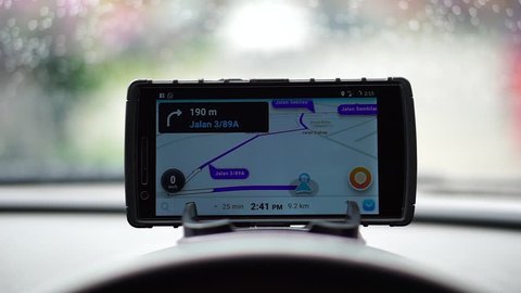 MALAYSIA, Kuala Lumpur, January 3, 2018: waze application on the smartphone shows the road direction on the car dashboard when the rains are visible in the windscreen  while the wiper works.