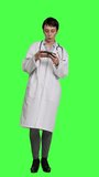 Front view General practitioner playing video games on mobile phone app, having fun with online gaming competition against greenscreen backdrop. Cheerful doctor relaxing with internet game. Camera A.