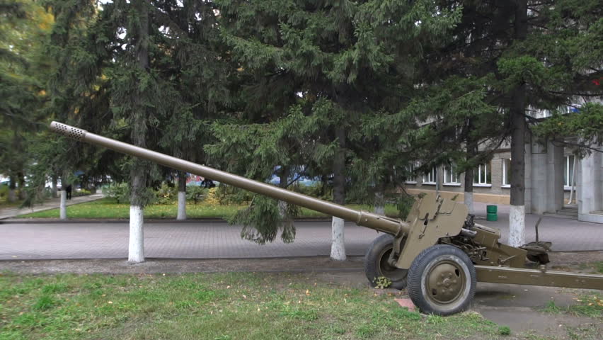 Main gun of artillery placed on pavement in green park. 