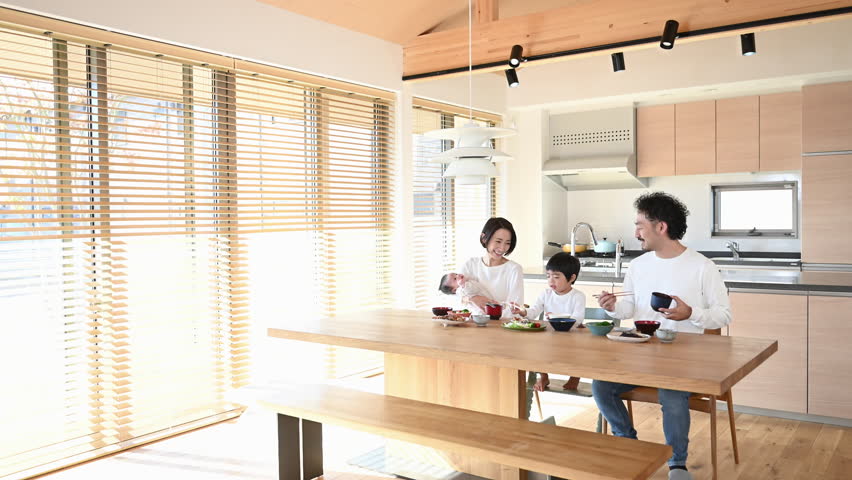 Smiling parents and children eating in a bright dining room.	