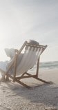 Vertical video of biracial woman alone on sunbed on sunny beach. healthy, active retirement beach holiday.