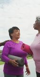 Vertical video of diverse female senior friends with yoga mats talking. active retirement lifestyle and senior relationship.
