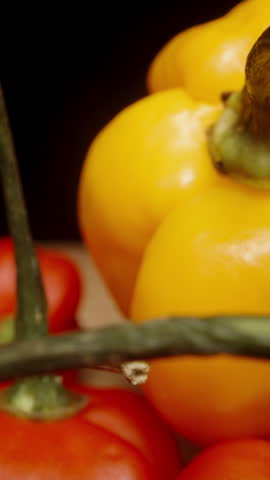 Vertical video. A scattering of a mixture of yellow and red hot peppers on the table, including Habanero and The Star of Turkey varieties. Dolly slider extreme close-up.
