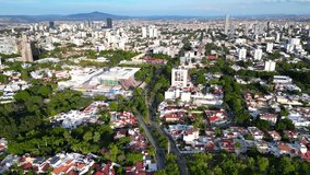 Sweeping drone footage flying over the vibrant Avenida Manuel Acuna and the roundabout in Guadalajara's Monraz neighborhood