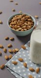 Vertical video of a bowl of almonds and bottle of milk on lilac background. healthy snack food, diet and nutrition.