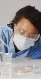 Vertical video of happy biracial female lab worker in face mask. science, medicine and working in laboratory concept.