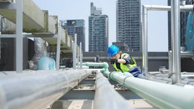 Asian woman engineer in safety uniform working and speaking on two way radios at outdoor construction site rooftop. Industrial technician worker maintenance checking building exterior plumbing systems - Powered by Shutterstock - Get 15% off with code: PIKWIZARD15