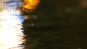 Multi-colored reflection of the night lights of the city in the water of a puddle. The video was shot at night in close-up during the rain and with a slight out of focus.
