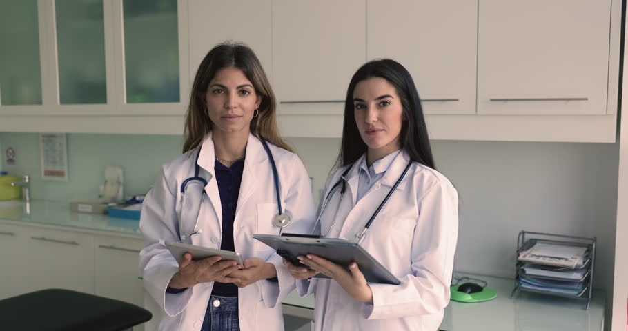 Portrait of two women Latin therapists, cardiologists, or attending physicians in white uniform posing at workplace, looking at camera. Career, professional medical services representatives, medicine Royalty-Free Stock Footage #3470263965
