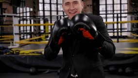 Portrait of a successful businessman in boxing gloves and a suit in a boxing ring, he jumps with happiness and laughs looking at the camera. - Powered by Shutterstock - Get 15% off with code: PIKWIZARD15