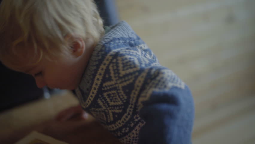 Close-Up Shot Of Blond Baby Boy In Blue Sweater Playing At Home - Fairbanks, Alaska
