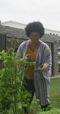 Vertical video of plus size biracial woman gardening. spending active time at home and body inclusivity.
