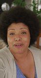 Vertical video of portrait of happy plus size biracial woman having video call and talking at home. spending active time at home and body inclusivity.