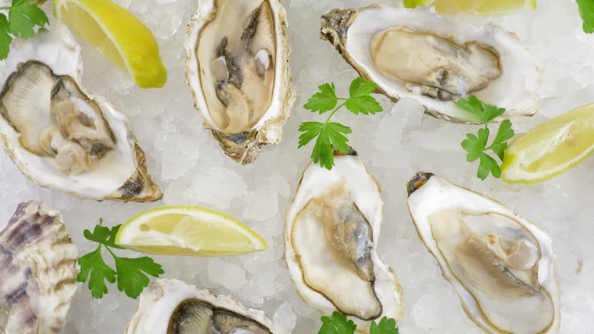 Pacific oysters. Half opened fresh mollusks on a plate with ice and lemon, view from top Royalty-Free Stock Footage #3470369489
