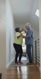 Vertical video of happy diverse senior couple dancing at home. active retirement lifestyle and senior relationship.