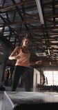 Vertical video of fit caucasian woman jumping on block at gym. active, fit, sporty and healthy lifestyle, exercising at gym concept.