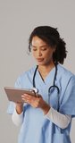 Vertical video of focused biracial female doctor making notes. health, medicine and doctor profession concept.