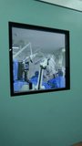 Approaching the door to a surgery room with square window. Surgical operation taking place inside of the room. Vertical video.