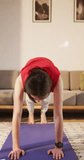 Vertical video of caucasian non-binary transgender woman practicing yoga, stretching. spending quality time at home alone, body inclusivity.