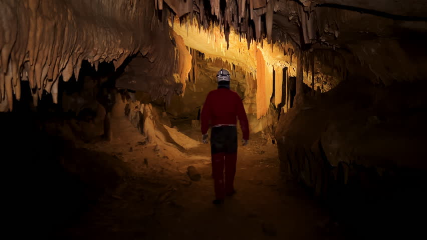 A speleologist with a headlamp exploring a cave with rich stalactite and stalagmite formations. High quality 4k footage Royalty-Free Stock Footage #3470495271